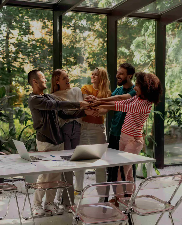 A group stacking their hands together around a table