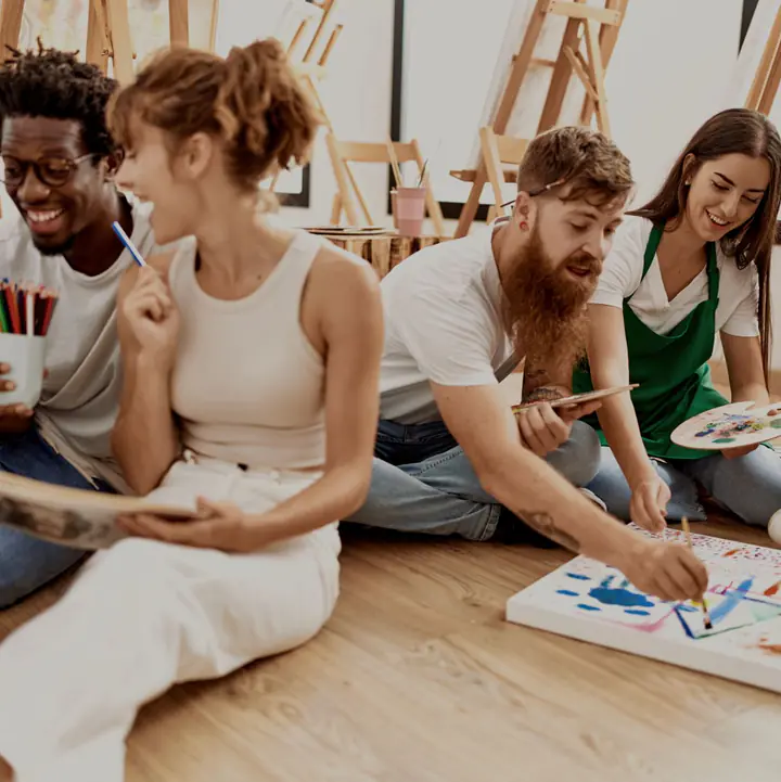 A group painting together on the floor of an art studio